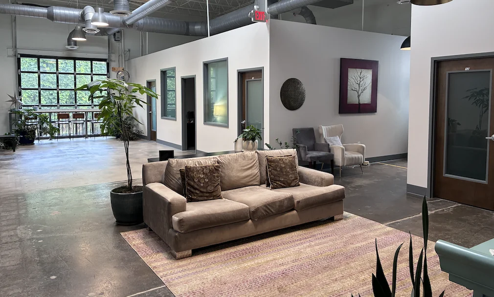 Shared indoor space at Midtown Psychotherapy Associates with a sofa, armchairs, plants, and large windows.